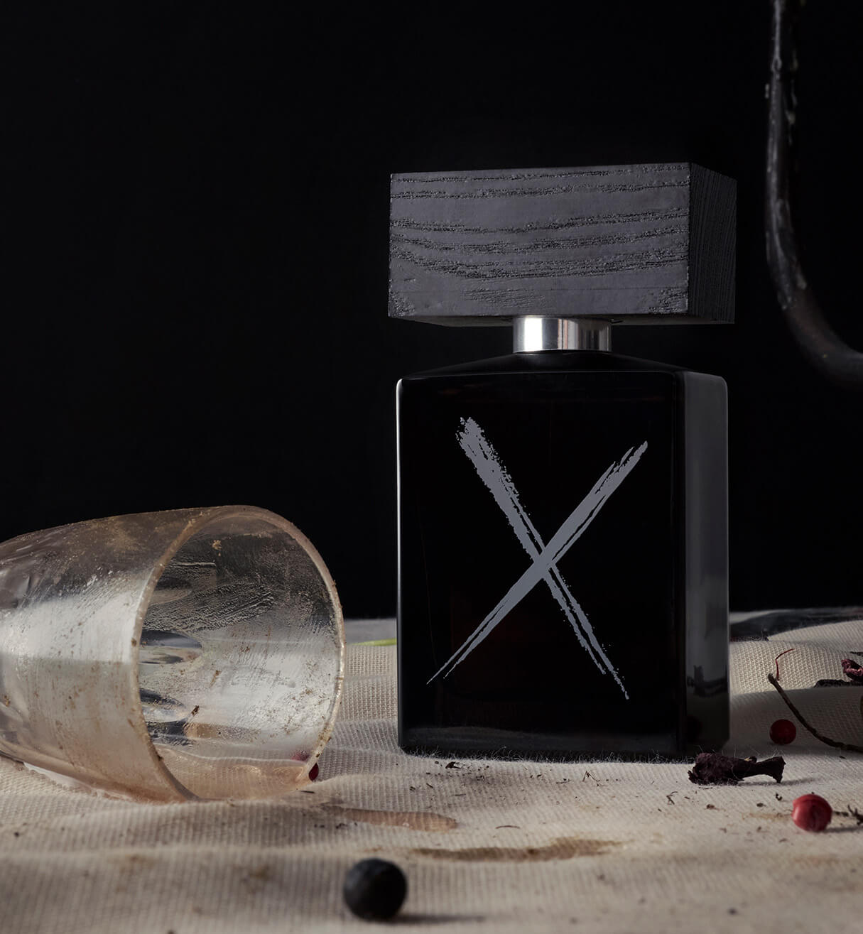 A bottle of BeauFort London's 'Rake & Ruin' Eau de Parfum, sat on a table with a tipped glass