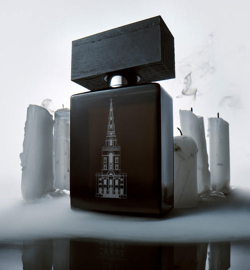 A bottle of BeauFort London's Terror & Magnificence Eau De Parfum, surrounded by freshly blown out candles